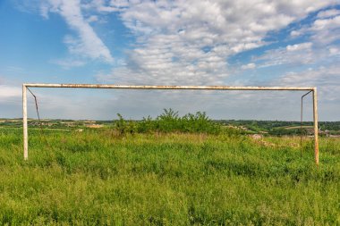 Terk edilmiş futbol sahası. Futbol sahasında çimenler ve kır çiçekleri..