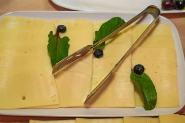 İnce dilimlenmiş bir tabak sarı gouda ve edam peyniri.