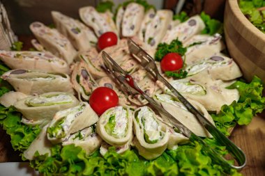 Tortilla dürüm aperatifleri, krem peynir ve et ile yakın plan parti tabağında.