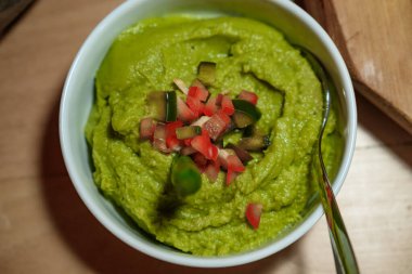 Domates ve salatalık gibi doğranmış sebzelerle süslenmiş yeşil bezelye spreyi..