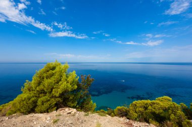 Yunanistan 'da açık mavi bir günde güneşli deniz kıyısına yakın uçurumlar. Turkuaz suyu ve açık mavi gökyüzü olan Pefkoulia plajı, Lefkada adası, İyon deniz kıyısı.