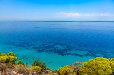 Yunanistan 'da açık mavi bir günde güneşli deniz kıyısına yakın uçurumlar. Turkuaz suyu ve açık mavi gökyüzü olan Pefkoulia plajı, Lefkada adası, İyon deniz kıyısı.
