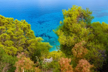 Yunanistan 'da açık mavi bir günde güneşli deniz kıyısına yakın uçurumlar. Turkuaz suyu ve açık mavi gökyüzü olan Pefkoulia plajı, Lefkada adası, İyon deniz kıyısı.