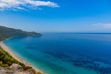 Yunanistan 'da açık mavi bir günde güneşli deniz kıyısına yakın uçurumlar. Turkuaz suyu ve açık mavi gökyüzü olan Pefkoulia plajı, Lefkada adası, İyon deniz kıyısı.