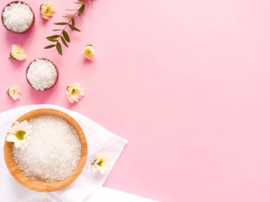 Spa yassı kompozisyonu. Deniz tuzu, banyo havlusu, çiçek, pembe arka planda bitki. Kopyalama alanı, üst görünüm. Evde bakım kavramı, rahatla ve dinlen..