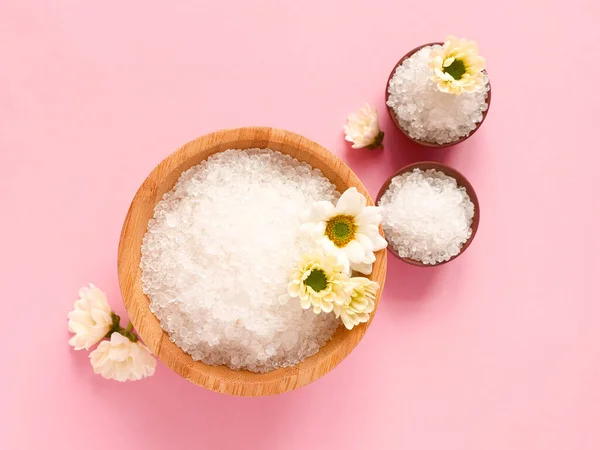 Spa yassı kompozisyonu. Kavanozlarda deniz tuzu, pembe arka planda çiçek. Yaklaş, üstten bak. Evde bakım kavramı, rahatla ve dinlen..