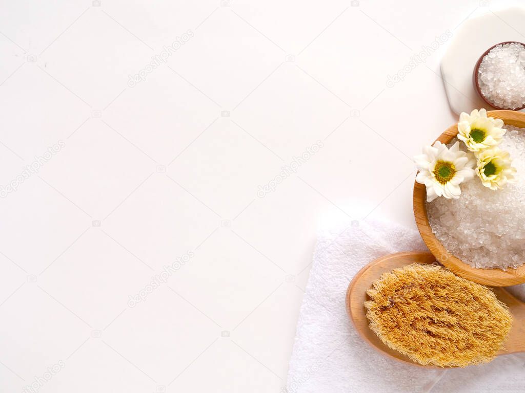 Spa flatlay composition. Sea salt, bath towel, massage wooden brush, flower on white background. Copyspace, top view. Home care concept, relax and rest.