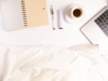 Düz kompozisyon dizüstü bilgisayar, kahve, kalem ve defter, beyaz masaüstünde battaniye. Kopyalama. Uzaktan çalışmayı ve evde çalışmayı kabul et, tele-çalışma, serbest çalışma, karantina. Çevrimiçi öğrenme mesafesi