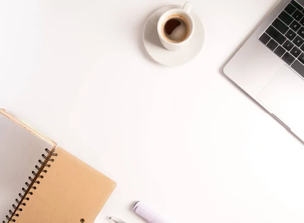 Düz konum dizüstü bilgisayar, kahve, kalem ve defter beyaz masaüstünde. Kopyalama. Uzaktan çalışmayı ve evde çalışmayı kabul et, tele-çalışma, serbest çalışma, karantina. Çevrim içi öğrenim
