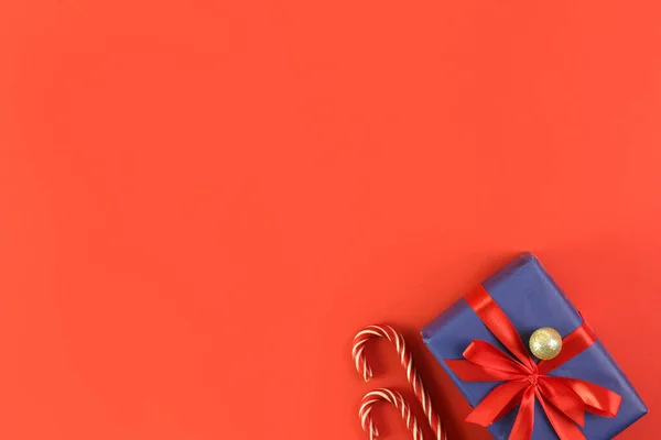 Kırmızı arka planda Noel hediyesi var. Tatil atmosferi, yeni yıl kutlamaları, tebrik kartları. Flatlay, üst görünüm.