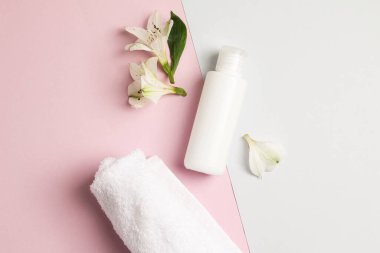 Krem, havlu, pembe ve mavi arka planda çiçekler eşliğinde yumuşak bez bileşimi. Güzellik kavramı doğal vitamin kozmetik ürünü, cilt bakımı, üst görünüm..