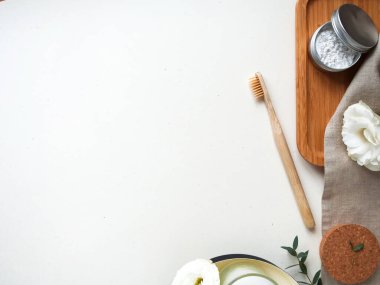 Doğal macun ve bej pamuk havluyla bambu diş fırçası, beyaz arka planda küçük bitki, yaprak, çiçek. Çevre dostu kavramı, kopyalama, sıfır atık.