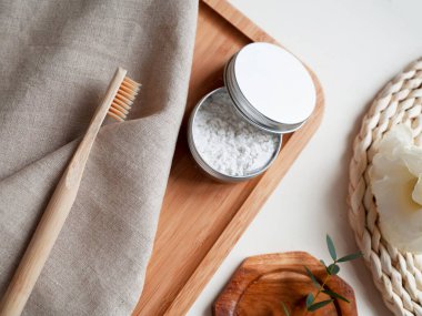 Bambu diş fırçası, doğal macun ve bej pamuklu havlu, beyaz arka planda küçük bir bitki. Çevre dostu kavramı, kopyalama, sıfır atık.