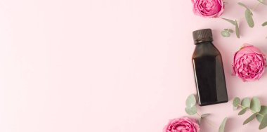 Losyonlu yumuşak bez, pembe arka planda çiçekler. Güzelliği kavramsal olarak doğal vitamin kozmetik ürünü, cilt bakımı, üst görünüm, kopyalanma alanı, afiş.