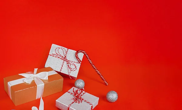 Hediye kutuları, dekoratif parıltı topları ve kırmızı arka planda şeker kamışı. Noel ya da yeni yıl konsepti