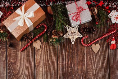 Parıltılı hediye kutuları, süsler, köknar ağacı, koniler, şeker kamışları ve tahta tahtalarda duran noel süsleri..