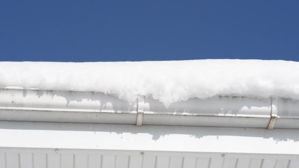 Sneeuw ligt op de dakrand en smelt onder invloed van de warme lentezon — Stockvideo