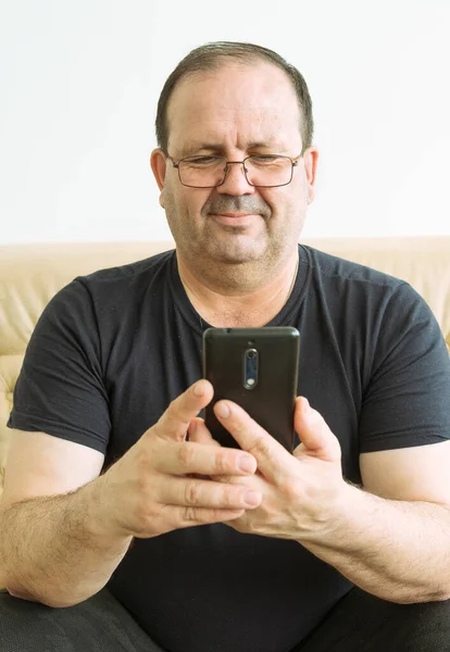 Adam elinde akıllı bir telefon tutuyor ve gülümsüyor.