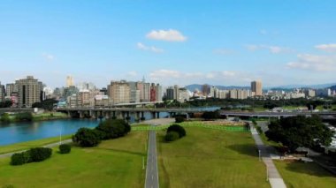 Taipei, Tayvan 'daki nehir kenarındaki parkın, mavi gökyüzünün altındaki şehrin ve beyaz bulutların havadan çekilmiş fotoğrafları.
