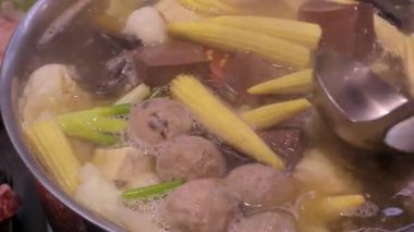 İçi lahana, mısır, tofu ve kızarmış tofu derisi gibi çeşitli malzemelerle dolu dumanı tüten bir tencere köpürüyor..