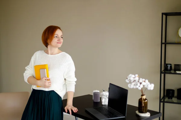 Red Haired Woman White Sweater Sits Table Laptop Background Beige — Stock Photo, Image