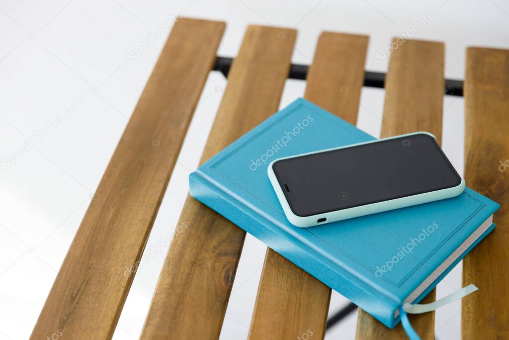 smartphone and notebook for planning affairs lie on wooden table against white wall background