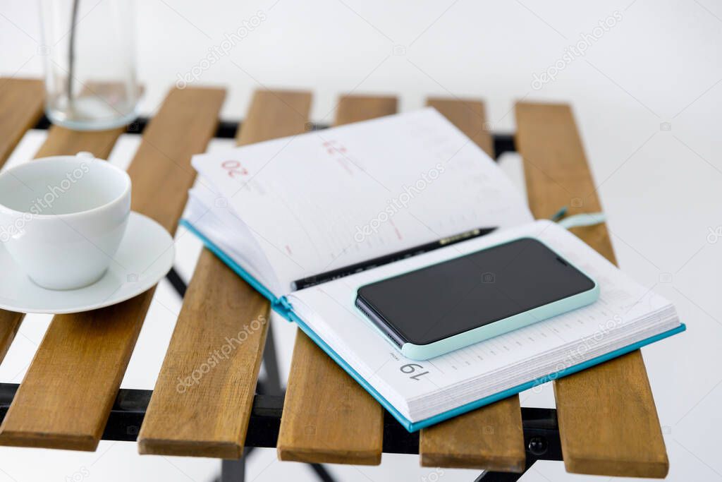 smartphone and notebook for planning affairs lie on wooden table
