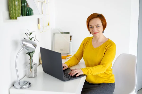 Red Haired Woman Yellow Sweater Sits Background White Wall Works — Stock Photo, Image