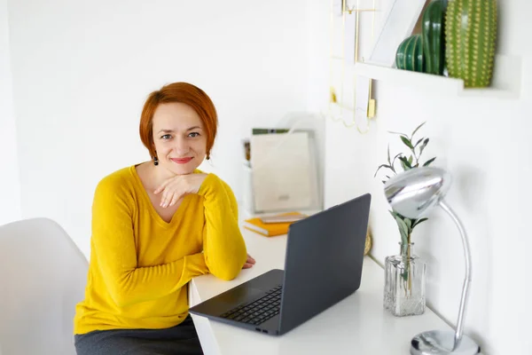 Red Haired Woman Yellow Sweater Sits Background White Wall Works — Stock Photo, Image