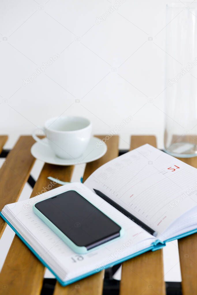 smartphone and notebook for planning affairs lie on wooden table