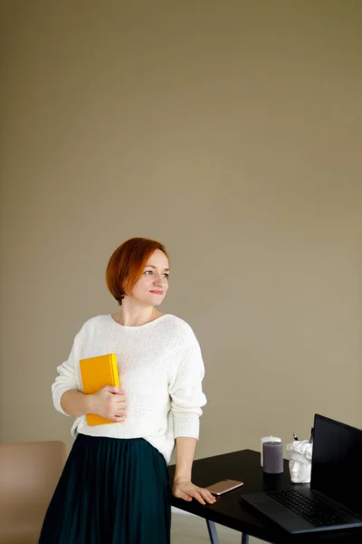 Red Haired Woman White Sweater Sits Table Laptop Background Beige — Stock Photo, Image