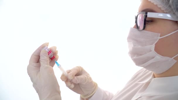 若い白人女性医師は、注射器とコロナウイルスワクチンのボトルを保持しています。コロナウイルス感染症の治療の概念, COVID-19ワクチン接種 — ストック動画