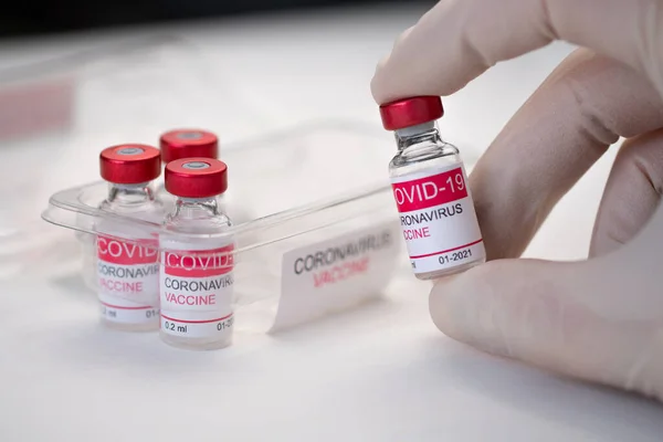 Yakından bir doktor elinde cam bir şişe koronavirüs aşısı tutuyor. Koronavirüs aşısı kavramı. Makro