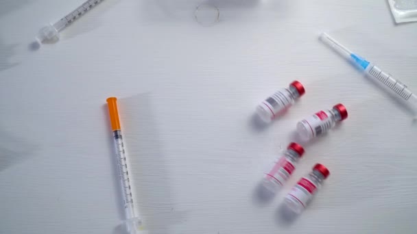 Top view vaccins voor de behandeling van coronavirus infectie rollen op een houten witte tafel. Concept van coronavirusvaccinatie. 4k — Stockvideo