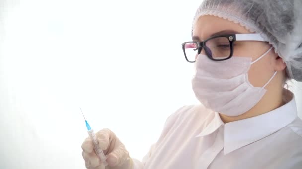 Νεαρή καυκάσια γιατρός κρατά μια σύριγγα και ένα μπουκάλι εμβόλιο για τον ιό της στέψης. Έννοια της θεραπείας της λοίμωξης από τον ιό Coronavirus, εμβολιασμός COVID-19 — Αρχείο Βίντεο
