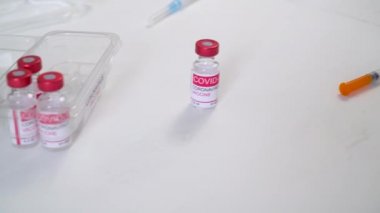 Doktorlar eldiven takıp Coronavirus aşısı ve şırınga şişelerini alıyorlar.