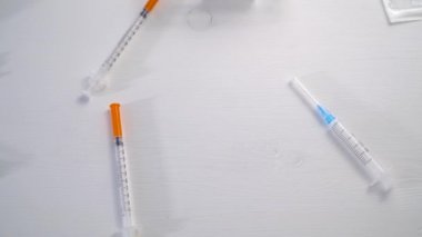 Coronavirus enfeksiyonunun tedavisinde kullanılan aşı şişeleri ahşap beyaz bir masada yuvarlanıyor.