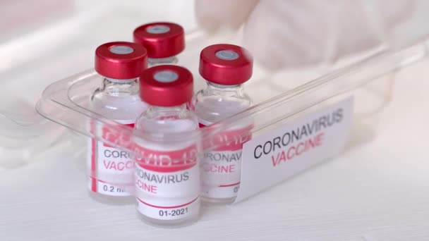Zbliżenie lekarzy wyciąga z opakowania fiolki ze szczepionką w celu leczenia zakażenia koronawirusem — Wideo stockowe