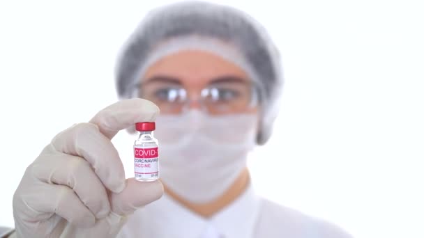 Close up of young female doctor holding and looking at a glass bottle of coronavirus vaccine. Concept of coronavirus vaccination — Stock Video