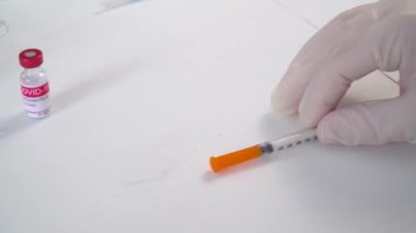 Eldivenli doktorlar Coronavirus aşısı olan şırınga ve şişeleri alıyorlar.