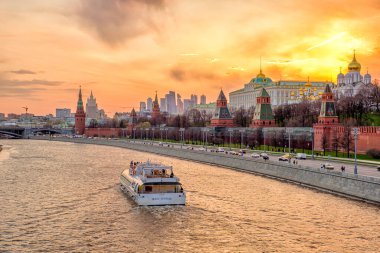 Moskova - 17 Nisan 2021: Moskova Kremlin 'de akşam manzaralı güzel gün batımı manzarası. Eğlence gemisi Moskova nehri boyunca ilerliyor..