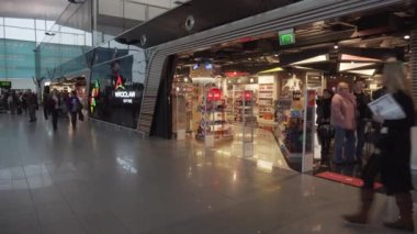 İnsanlar Kopernik Havalimanı Wroclaw 'daki gümrüksüz mağaza girişinin önünde yürüyorlar - Pan sağdan, 4K