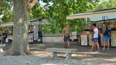 Roma 'daki Castel SantAngelo yakınlarında yeşil ağaçlar ve hediyelik eşya tezgahları olan insanlar - 4K, Pan, El bilgisayarı