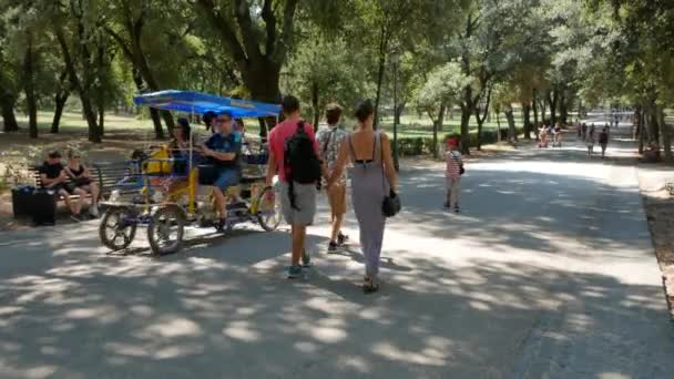 Люди гуляют и ездят на велосипедах по ледяной дорожке в садах Вилла Боргезе в Риме - 4K, ручная, велосипедная — стоковое видео