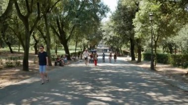 Roma 'daki Villa Borghese bahçelerinde insanlar yürüyor ve bisiklete biniyor - 4K, El bilgisayarı, Editör