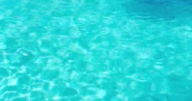 PORTOCOLOM, MALLORCA, İSPA - ECTOBER 2025: Yumuşak dalgalar bir yüzme havuzu yüzeyinde hareket ederek, tatil sırasında güneş ışığını yansıtır.