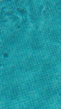 PORTOCOLOM, MALLORCA, İSPA - ECTOBER, 2025: Yakın plan yüzme havuzundaki yumuşak su dalgalarını ortaya çıkarıyor, güneş ışığı havuz zemininde desenler oluşturuyor, geniş açı, yaz arkaplanı.