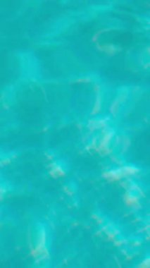 PORTOCOLOM, MALLORCA, İSPA - ECTOBER, 2025: Gün ışığı berrak, turkuaz bir havuzda parlar, hafif dalgalar su yüzeyinde hareket ederek, sakin bir yaz arkaplanı oluşturur.