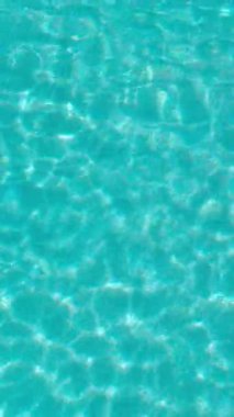 PORTOCOLOM, MALLORCA, İSPA - ECTOBER 2025: Yüzme havuzuna yakın, güneş ışığı yüzeyde yansıyor güzel dalgalar yaratıyor, yaz, dinlenme ve tatil için mükemmel bir zemin.