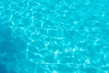Parlak turkuaz su gösterilir. Güneş ışığı tatil sırasında yüzme havuzunun yüzeyinde desenler ve dalgalanmalar yaratır..